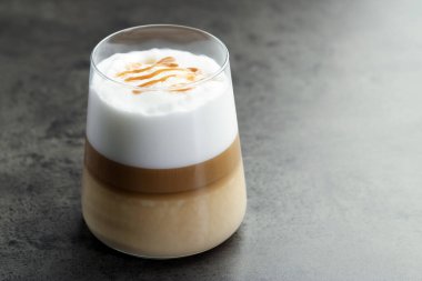 Tasty latte macchiato in glass on grey table, closeup. Space for text