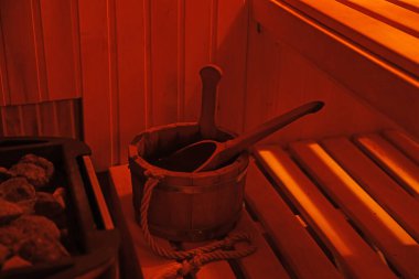 Bucket with ladle on wooden bench in sauna