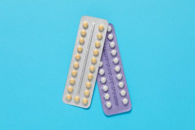 Blisters of contraceptive pills on light blue background, top view