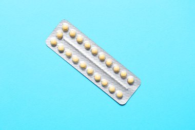 Blister of contraceptive pills on light blue background, top view