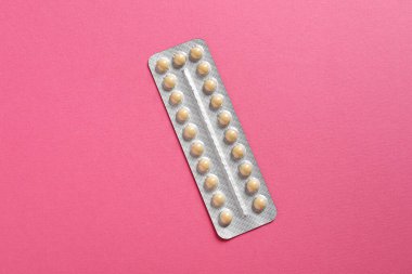 Blister of contraceptive pills on pink background, top view