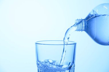 Açık mavi arka planda şişeden cama soda dökmek, yakın plan. Metin için boşluk