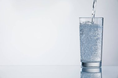 Açık gri arka planda ferahlatıcı soda bardağına dökülüyor, yakın plan. Metin için boşluk