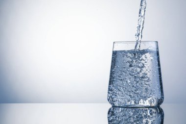 Açık gri arka planda ferahlatıcı soda bardağına dökülüyor, yakın plan. Metin için boşluk