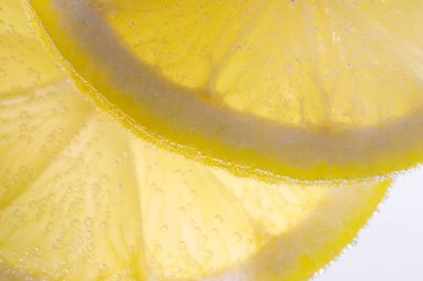 Arka planda limon dilimleri olan soda, yakın plan.