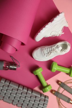 Pembe arka planda farklı spor malzemeleri, düz yatış.