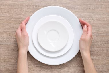 Ahşap masada seramik tabaklar taşıyan bir kadın.