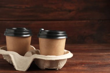 Kağıt kahve bardakları ahşap masadaki karton tutacakta, yakın plan. Metin için boşluk