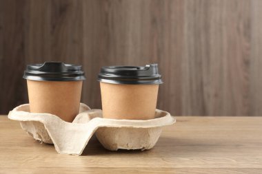 Kağıt kahve bardakları ahşap masadaki karton tutacakta, yakın plan. Metin için boşluk