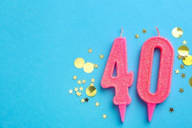 40th birthday. Number shaped candles and confetti on light blue background, flat lay. Space for text