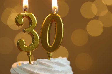 30. yaş günü. Kek üzerindeki mumların yanma sayısı altın arka planda bulanık ışıklar, yakın çekim ve metin için boşluk. Bokeh etkisi