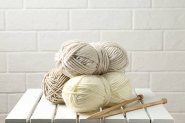 Skeins of yarn and knitting needles on white wooden table