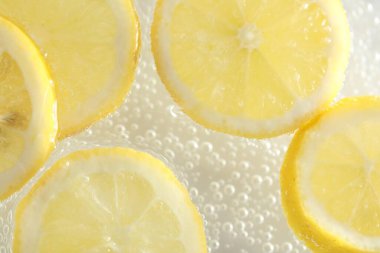 Arka planda limon dilimleri olan soda, yakın plan.