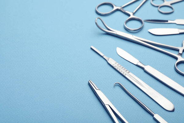 Different surgical tools on light blue background, closeup. Space for text