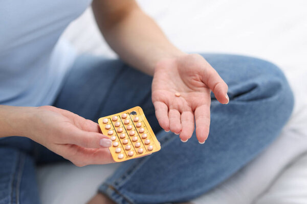 Woman with contraceptive pills on bed, closeup