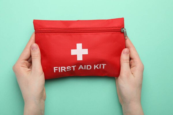Женщина с аптечкой на бирюзовом фоне, вид сверху