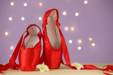 Bulanık ışıklara karşı bej masanın üzerinde bir çift şık puanlı ayakkabı ve çiçek. Metin için boşluk