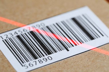 Etiketli paket, yakın plan. Tarama için barkodda kırmızı lazer ışığı