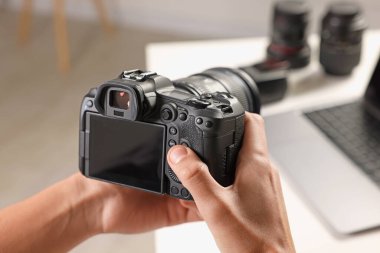 Beyaz masadaki profesyonel kameralı fotoğrafçı, yakın plan.