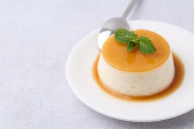 Tasty pudding with caramel sauce served on white table, closeup. Space for text