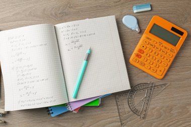 Doing homework. Notebook with math assignment and stationery on wooden desk, flat lay