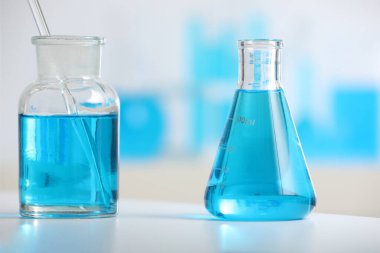 İçerideki masada sıvı bulunan laboratuvar camları, yakın plan.