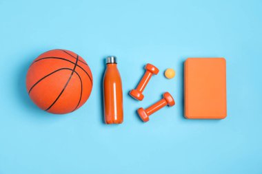 Açık mavi arka planda farklı spor aletleri ve su şişesi, düz yatıyordu.