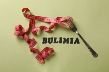 Kelime Bulimia, ölçüm bandı ve çatal zeytin arka planda, üst görünüm