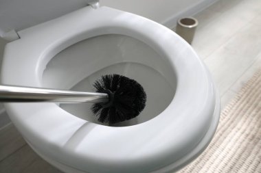 Cleaning toilet bowl with brush indoors, closeup