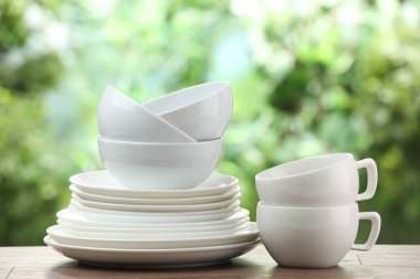 Clean dishware on wooden table against blurred background