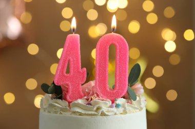 40th birthday. Tasty cake with burning number shaped candles and sprinkles on blurred background with lights, closeup. Bokeh effect