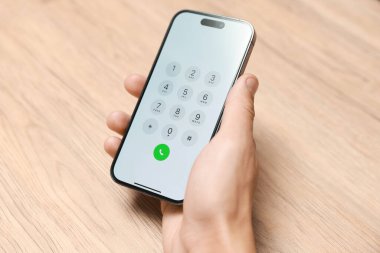 Ahşap masada elinde tuş takımı olan akıllı telefon tutan adam, yakın plan.