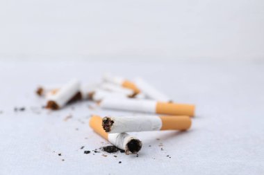 Many cigarette butts on light background, closeup