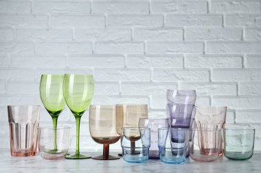 Tuğla duvara karşı beyaz mermer masada bir sürü farklı bardak var. Metin için boşluk