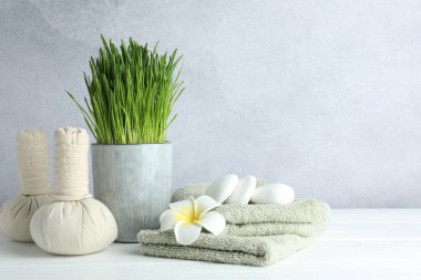 Spa composition with wheatgrass on white table against light grey background. Space for text