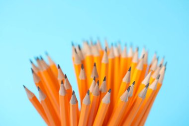 Many graphite pencils on light blue background, closeup
