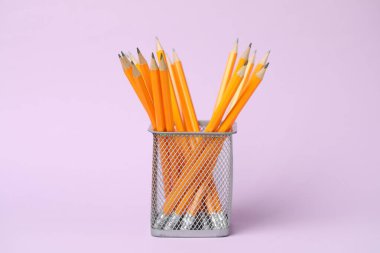 Many graphite pencils in holder on pink background