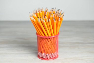 Many graphite pencils in holder on wooden table
