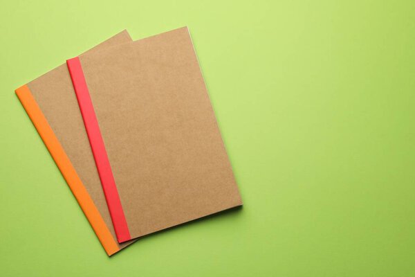 Two copybooks on green background, flat lay. space for text