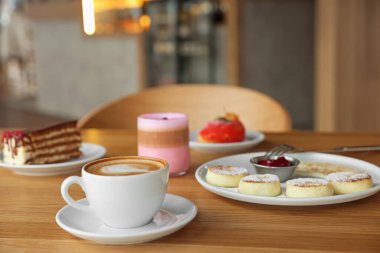 Lezzetli süzme peynir krepleri, tatlılar ve kafedeki ahşap masada servis edilen aromatik kahve.