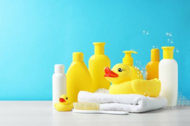 Bebek kozmetik ürünleri, plastik ördekler ve gri masada açık mavi arka planda uçan baloncuklar. Metin için boşluk