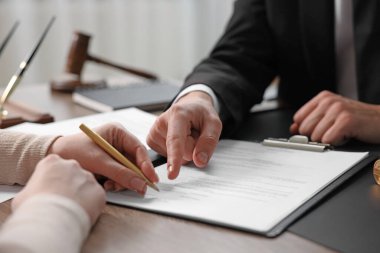 Belgeye işaret eden noter ve müşterinin masa içine imza koyması, yakın plan