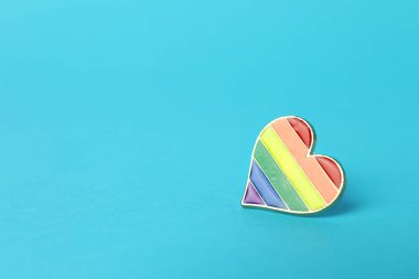 Heart shaped badge in LGBT colors on light blue background, space for text