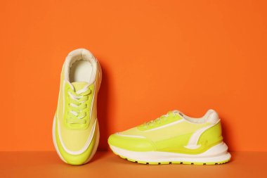 Stylish neon lime sneakers on color background