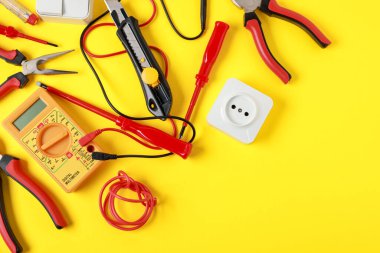 Different electrical tools on yellow background, flat lay. Space for text