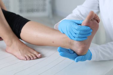 Hastanedeki hastanın ayağını muayene eden doktor, yakın plan.