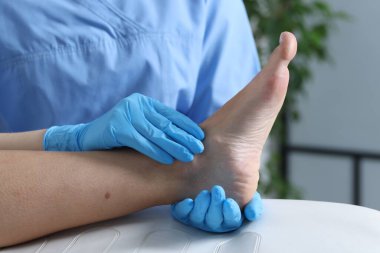 Hastanedeki hastanın ayağını muayene eden doktor, yakın plan.