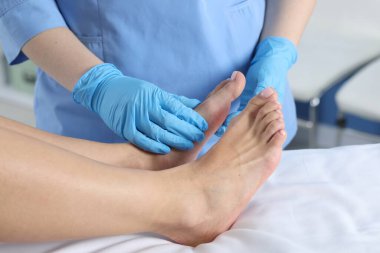 Hastanedeki hastanın ayağını muayene eden doktor, yakın plan.