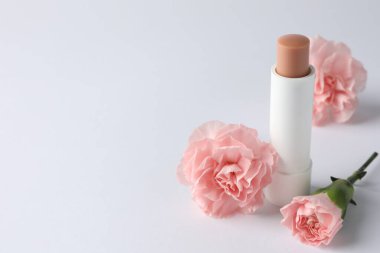 Beyaz arka planda dudak kremi ve Eustoma çiçekleri, yakın plan. Metin için boşluk