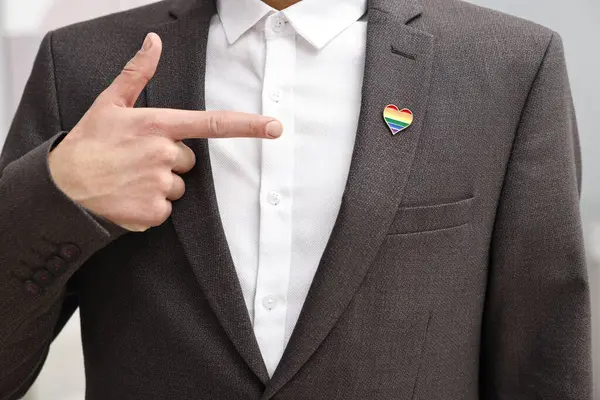 Kalbe bakan adam, kapalı alanda LGBT bayrağı renginde iğne şeklinde, yakın plan.